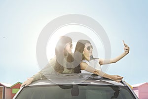 Young women taking selfie photo on car sunroof photo