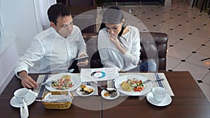 Young woman talking on the phone during lunch and asking her male partner for help photo