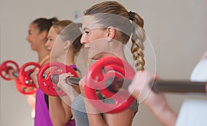 Young women training with barbells in fitness class