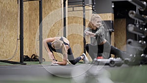 Young women are training together in fitness center in gym, stretching legs muscles, group workout