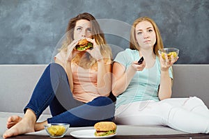 Young women with tv remote eating fast food