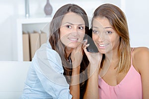Young women using listening to same phone conversation