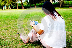 Young women using table ipad while sitting on grass in the park,digital technology
