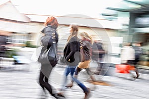 Young women walking against shop window at dusk, zoom effect, mo