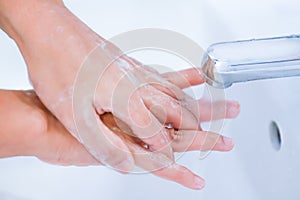 young women washing hands with soap rubbing fingers under faucet water flows for pandemic prevention covid-19