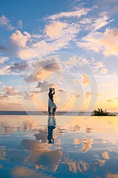 Young women watching sunset with reflection in the infinity pool at Saint Lucia Caribean