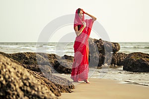 Young women wearing a red saree on the beach goa India.girl in traditional indian sari on the shore of a paradise island