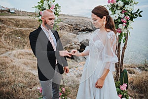 Young women in a white dress puts a ring on the finger of a man in a suit. Wedding ceremony