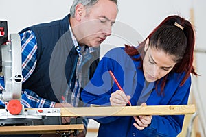 Young woman working at carpenter shop with teacher