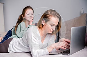 Young women works at home with laptop along with two children.Children want to communicate with mother, make noise and interfere