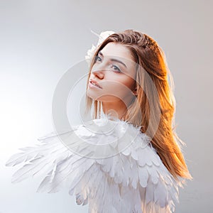 Young, wonderful blonde girl in the image of an angel with white wings.