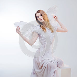 Young, wonderful blonde girl in the image of an angel with white wings.