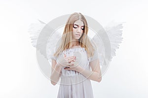 An angel from heaven gives you a hand. Young, wonderful blonde girl in the image of an angel with white wings.