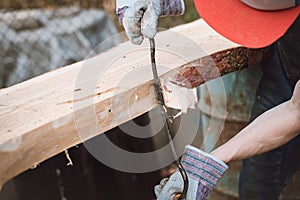 Young woodcutter prepares larch wood for later processing. Planing wood. Working larch boards with traditional tools. Hand