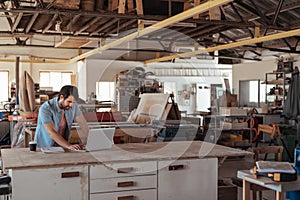 Young woodworker working online at a bench in his workshop photo