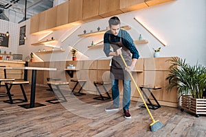 Worker cleaning floor with sweep photo