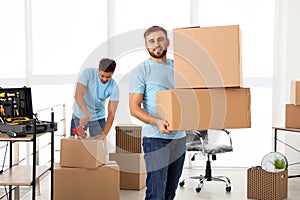 Young worker with cardboard  and his colleague in office. Moving service