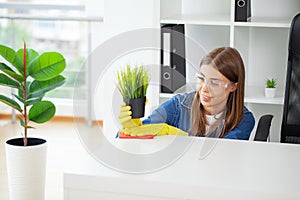 Young Worker Cleaning Desk With Rag In Office