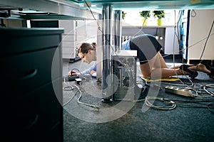 Young worker connecting cables and wires to computer in office