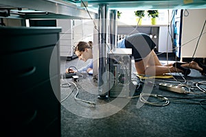 Young worker connecting cables and wires to computer in office photo