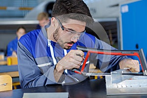 young worker cutting metal frame