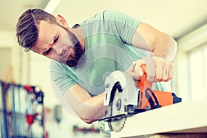 Young worker in a carpenters workshop with hand saw photo