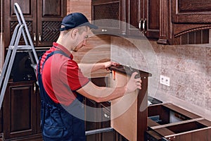 A young worker installs a drawer. Installation of modern wooden kitchen furniture