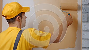 Young worker painting wall indoors.