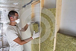 Young worker in respirator insulating rock wool insulation staff