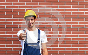 Young worker showing tumb up in front of a brick wall photo