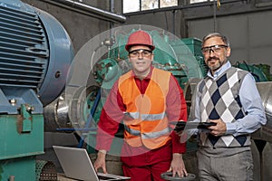 Young Worker Using Laptop Computer for Data Checking With Technical Manager in Power Plant