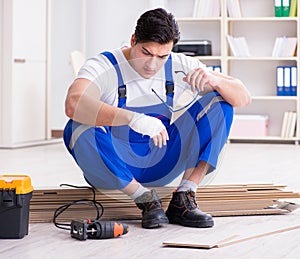 Young worker working on floor laminate tiles