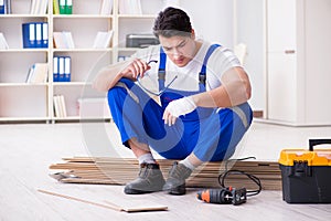 The young worker working on floor laminate tiles