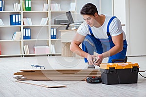 The young worker working on floor laminate tiles