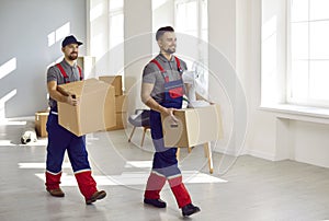 Young workers from moving company and delivery service removing boxes from apartment