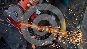 Young workers use metal grinders Steel parts of a motorbike To design and modify Beautiful orange sparkle from metal grinding