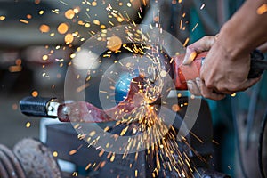 Young workers use metal grinders Steel parts of a motorbike To design and modify Beautiful orange sparkle from metal grinding