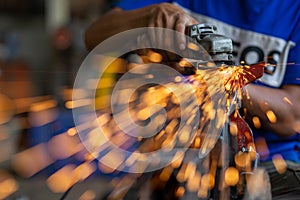 Young workers use metal grinders Steel parts of a motorbike To design and modify Beautiful orange sparkle from metal grinding