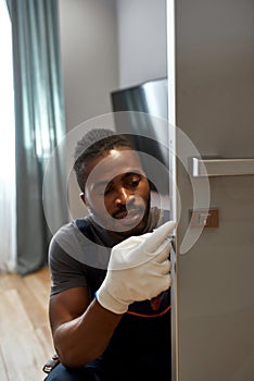 Young workman fixing living room door lock