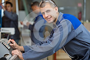 young workman operating machines in industrial shop