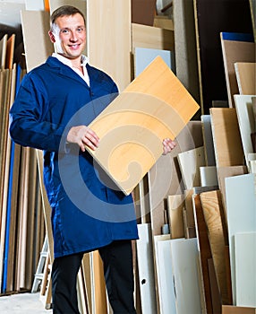 Young workman standing with plywood pieces