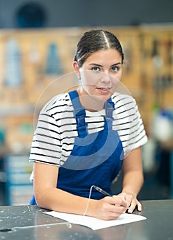 Young workwoman filling out paperwork in bike workshop