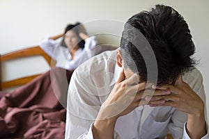 Young worried man on bed. Unhappy couple having problem in bedroom. photo