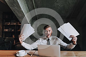 Young worried man holding many paper sheets