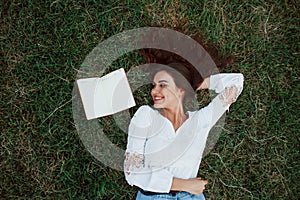 Young writter. Girl lying down on the green grass and have a rest photo