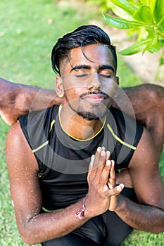 Young yoga man practitioners doing yoga on nature. Asian indian yogis man on the grass in the park. Bali island.