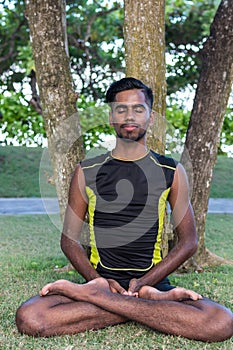 Young yoga man practitioners doing yoga on nature. Asian indian yogis man on the grass in the park. Bali island.