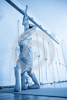 Young yoga woman standing on head during yoga class