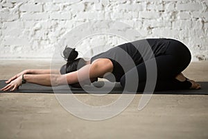 Young yogi attractive woman in Child pose, white loft background