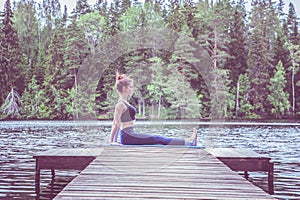 Young yogi  girl  practicing yoga, sitting in Staff exercise, Dandasana pose on the lake. The concept of appeasement,  healthy